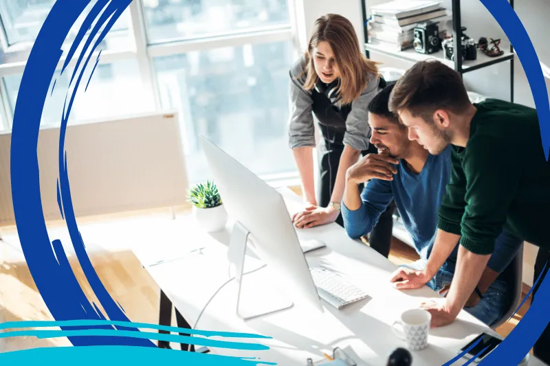 A group of marketers gathered around a computer, collaborating on ChatGPT prompts to generate marketing ideas.